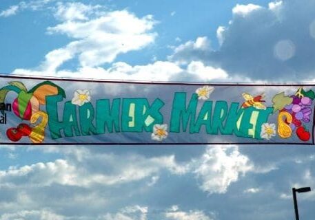 A banner that says farmers market with flowers on it.