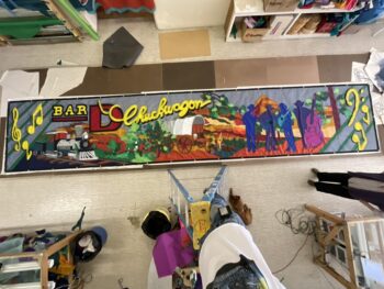 A colorful mural depicts a western scene with a train, wagon, bar sign, musical notes, and silhouettes of people.