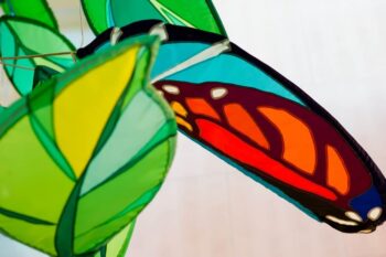Close-up of colorful, translucent butterfly and leaf decorations against a softly blurred background.